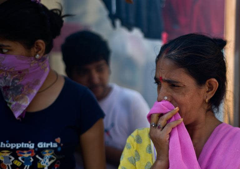 Indian women cover their faces from smoke after a municipal health worker fumigated against mosquitoes at a neighborhood in New Delhi on October 3, 2013