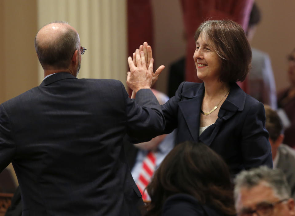 FILE - Sen. Nancy Skinner, D-Berkeley, and Sen. Steven Glazer, D-Orinda slap palms in celebration after her measure to let athletes at California colleges hire agents and sign endorsement deals was approved by the Senate in Sacramento, Calif., in this Wednesday, Sept. 11, 2019, file photo. The NCAA Board of Directors is expected to greenlight one of the biggest changes in the history of college athletics when it clears the way for athletes to start earning money based on their fame and celebrity without fear of endangering their eligibility or putting their school in jeopardy of violating amateurism rules that have stood for decades.(AP Photo/Rich Pedroncelli, File)