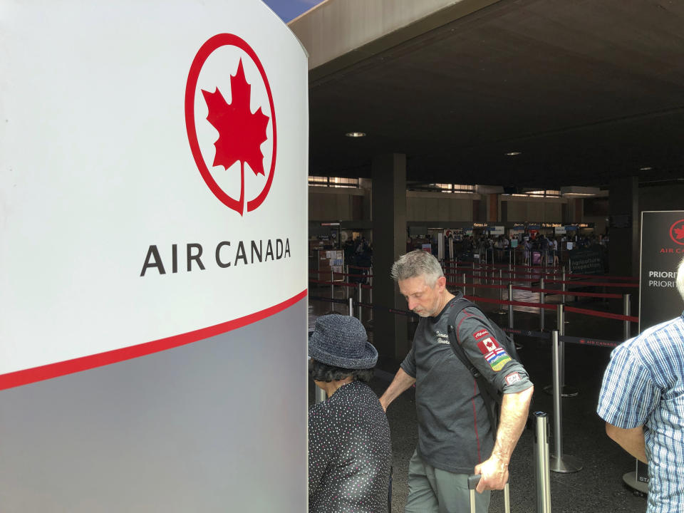 Passengers from an Australia-bound Air Canada flight diverted to Honolulu Thursday, July 11, 2019, after about 35 people were injured during turbulence, stand in line at the Air Canada counter at Daniel K. Inouye International Airport to rebook flights. Air Canada said the flight from Vancouver to Sydney encountered "un-forecasted and sudden turbulence," about two hours past Hawaii when the plane diverted to Honolulu. (AP Photo/Caleb Jones)