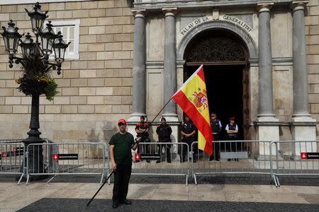 A man hold up a Spanish flag next to Mossos d'Esquadra, Catalan regional police, standing guard outside the Palau de la Generalitat, the regional government headquarters, during a demonstration in favor of a unified Spain a day before the banned October 1 independence referendum, in Barcelona, Spain, September 30, 2017. REUTERS/Susana Vera