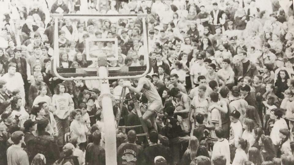 Watertown's Lonnie Struckman, watched by hundreds of Watertown fans, steps down a ladder after snipping a few strands from the net from the Arrows' 62-59 win over Sioux Falls O'Gorman in the District 1AA Boys Basketball Championship in March of 1992.