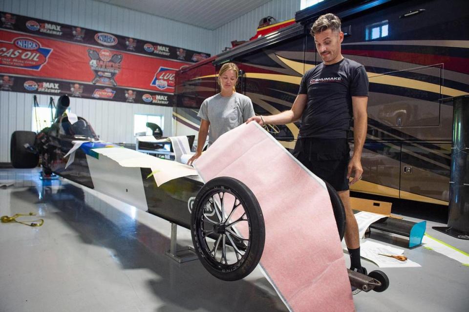 Drag racer Travis Shumake works with race team manager Megan Lingner to get sponsorship decals added to the dragster Shumake will be competing in at Heartland Motorsports Park in Topeka this weekend. 