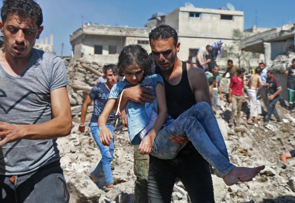 A man carries a child rescued from rubble after Syrian regime and Russian air strikes in the rebel-held town of Nawa, about 30 kilometres north of Daraa in southern Syria, on 26 June 2018: AFP/Getty