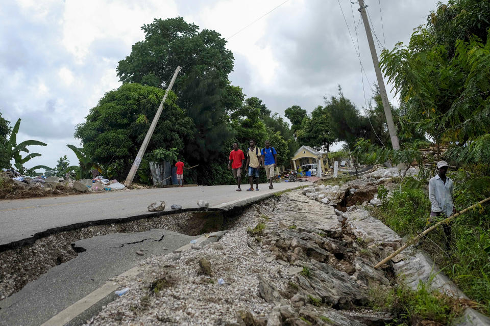 Residents walk on a damaged road in Rampe, Haiti, Wednesday, Aug. 18, 2021, four days after 7.2-magnitude earthquake hit the southwestern part of the country. (AP Photo/Matias Delacroix)