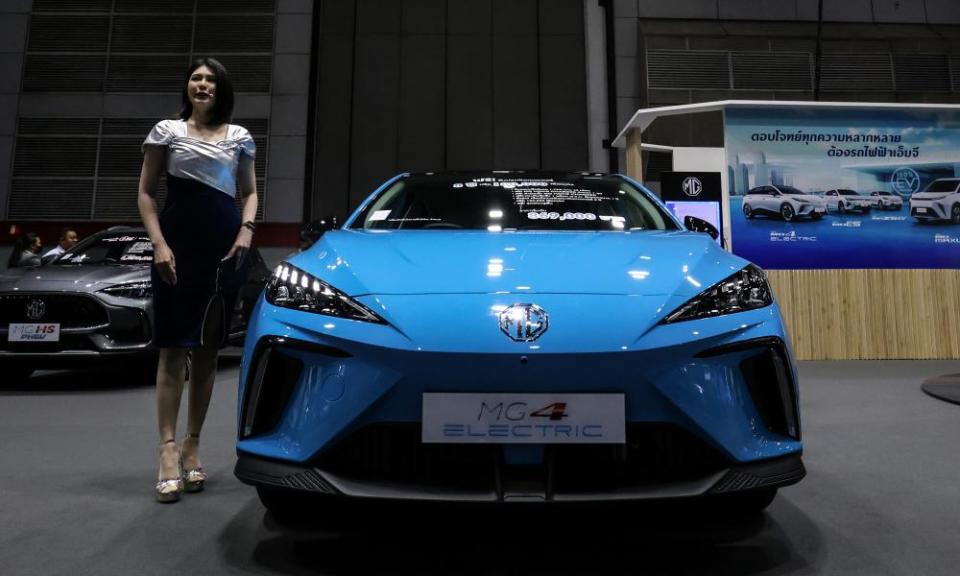 A futuristic looking blue hatchback with a woman standing next to it