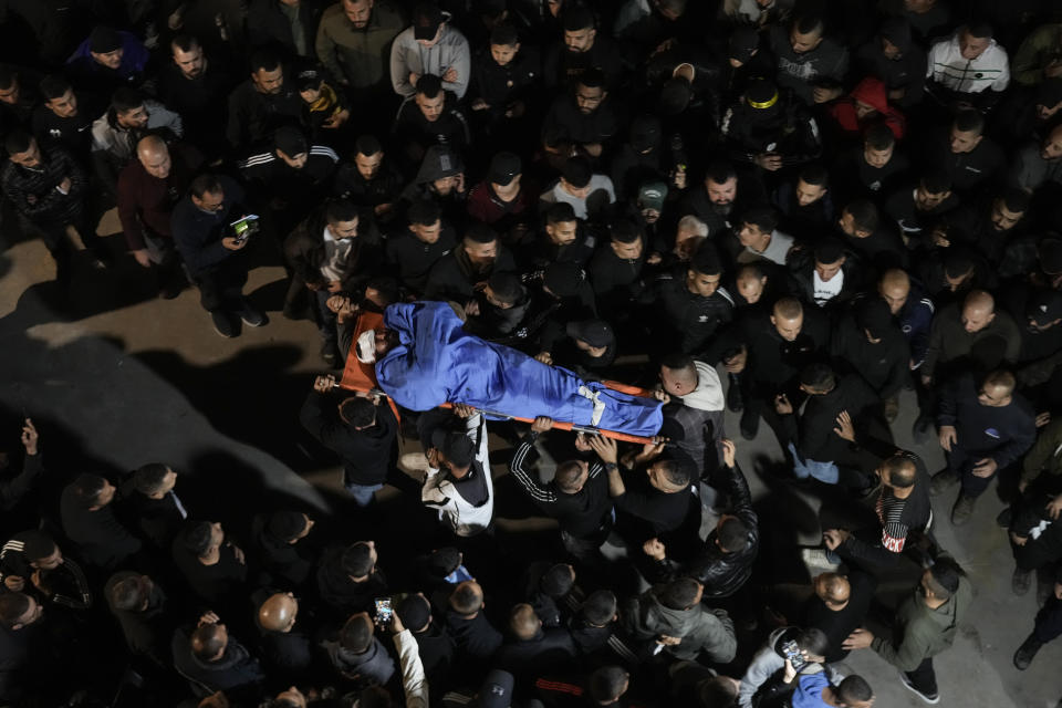 Palestinians carry the body of a man who was killed during an Israeli military raid in the West Bank city of Jenin, Tuesday, March 7, 2023. The Israeli army raided the occupied West Bank city of Jenin, leading to a gunbattle that killed at least six Palestinians. The Israeli military said it killed the assailant who was behind the fatal shooting of Israeli brothers in a West Bank town last week. (AP Photo/Majdi Mohammed)