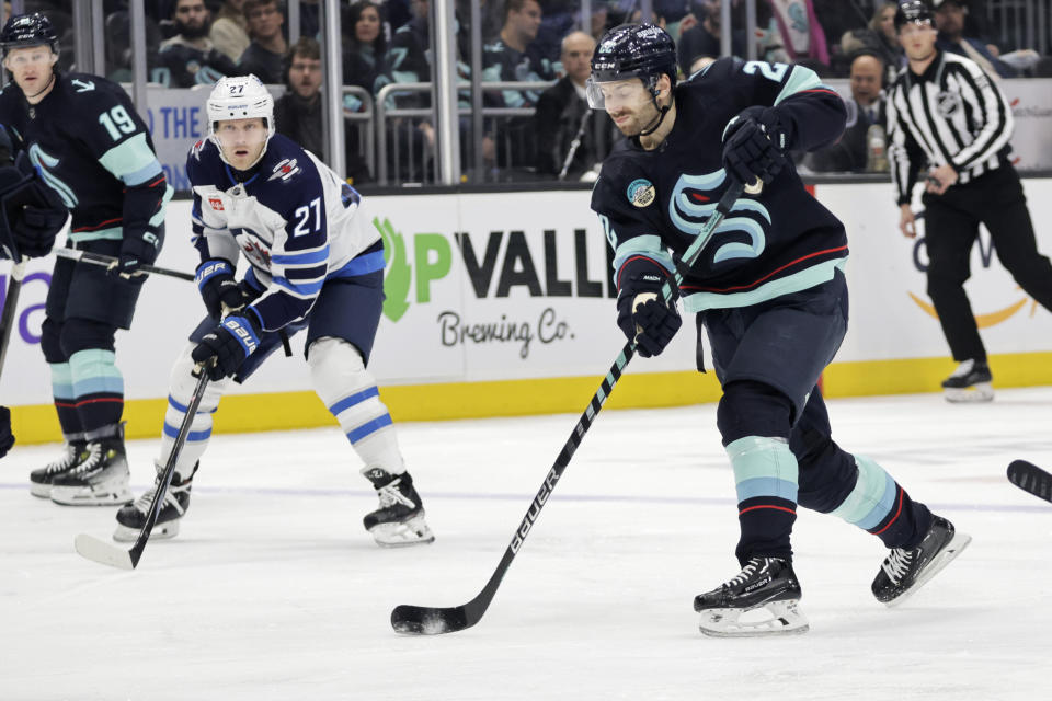 Seattle Kraken right wing Oliver Bjorkstrand (22) shoots on goal but is blocked Winnipeg Jets left wing Nikolaj Ehlers (27) watching during the first period of an NHL hockey game, Friday, March 8, 2024, in Seattle. (AP Photo/John Froschauer)