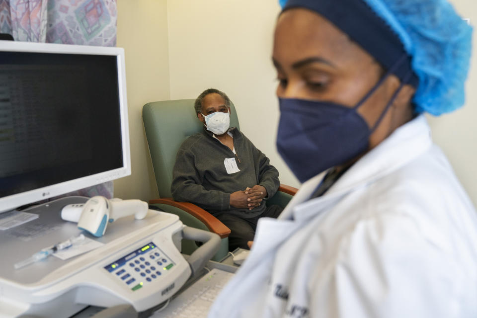 In this Wednesday, Feb. 10, 2021, photo the Rev. James Coleman, 70, waits as his COVID-19 vaccine is prepared by nurse practitioner Ifreke Udodong, at United Medical Center in southeast Washington. (AP Photo/Jacquelyn Martin)