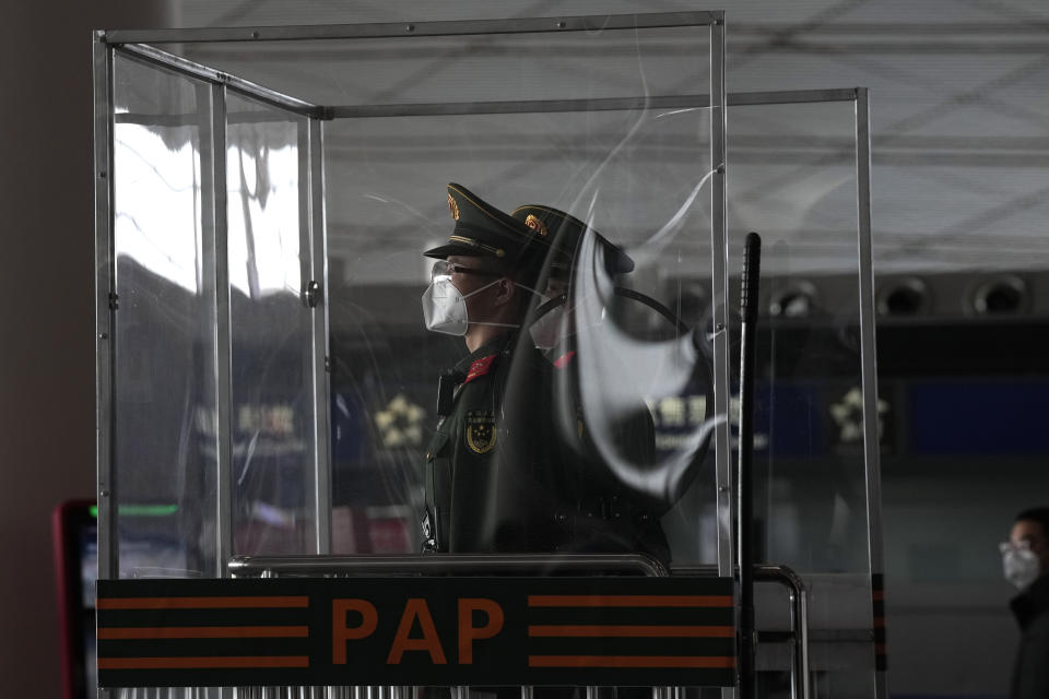 Chinese paramilitary police officers wearing masks stand guard at their post at the Capital airport terminal in Beijing, Tuesday, Dec. 13, 2022. Some Chinese universities say they will allow students to finish the semester from home in hopes of reducing the potential of a bigger COVID-19 outbreak during the January Lunar New Year travel rush. (AP Photo/Ng Han Guan)