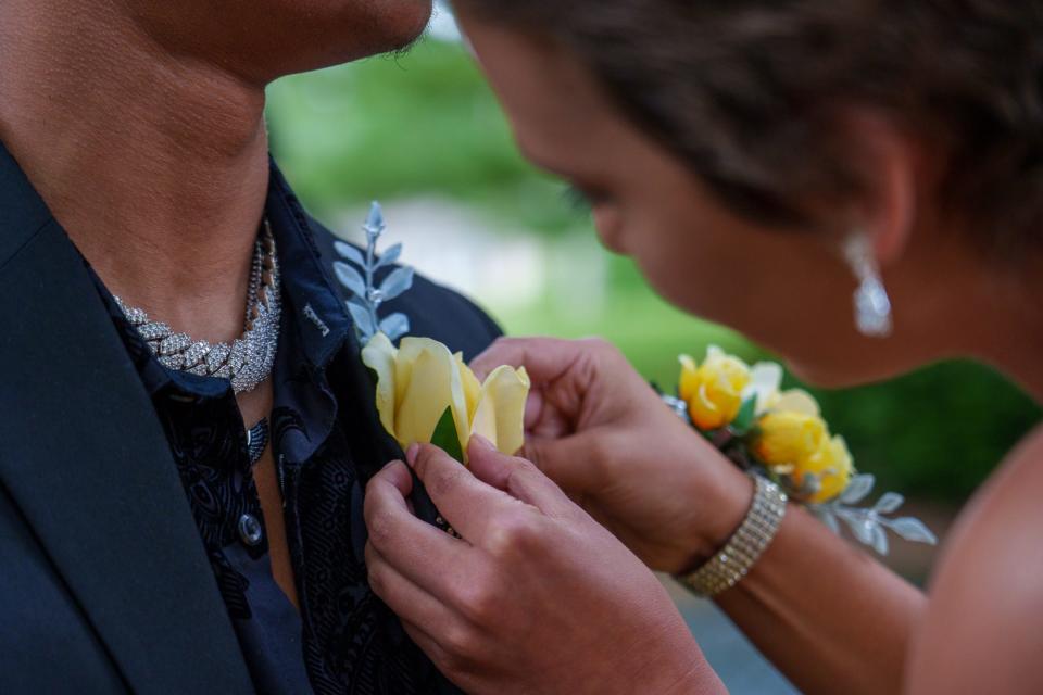 Vivian Eagle, 17, junior at Avon High School, pins a boutonniere on the jacket of Cade Thompson on Saturday, May 13, 2023, at Friendship Gardens Park in Plainfield, Indiana.
