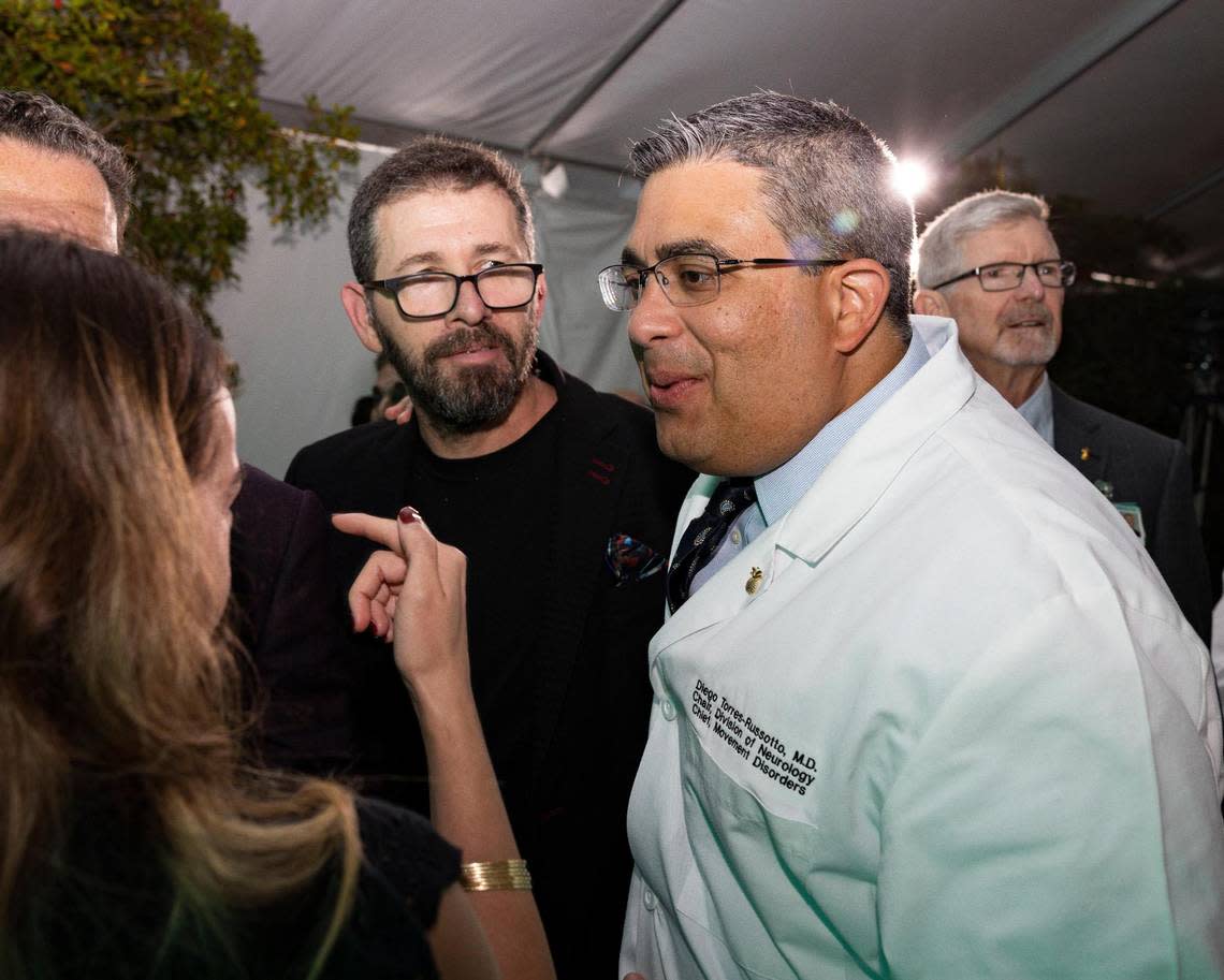 Sebastian Krys, Latin Grammy Award winner and Parkinson’s patient, center, smiles at his doctor, Dr. Diego Torres-Russotto, right, after a ceremony recognizing Ken Griffin, Citadel CEO, for his donation to the Miami Neuroscience Institute on Tuesday, March 19, 2024, at the Baptist Health Baptist Hospital in Miami, Fla. Alie Skowronski/askowronski@miamiherald.com