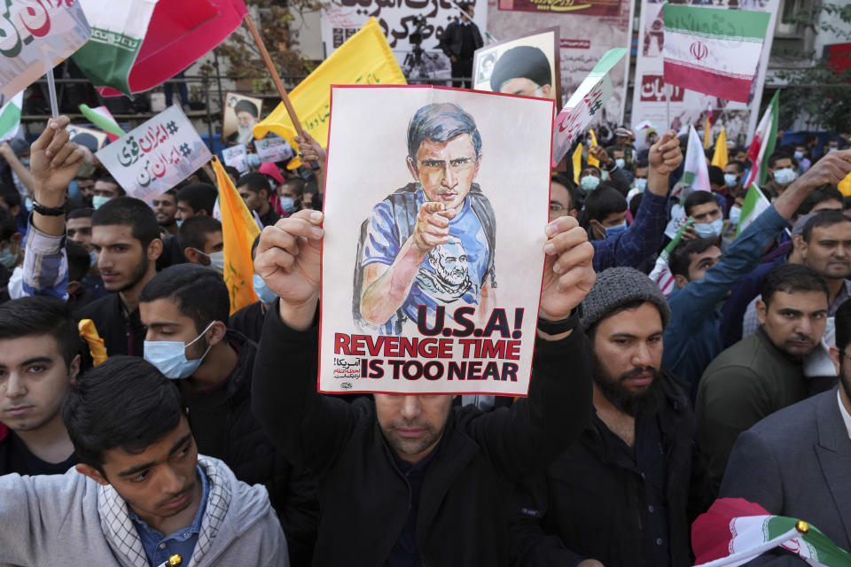 A man holds up an anti-U.S. placard during an annual demonstration in front of the former U.S. Embassy in Tehran, Iran, Friday, Nov. 4, 2022. Iran on Friday marked the 1979 takeover of the U.S. Embassy in Tehran as its theocracy faces nationwide protests after the death of a 22-year-old woman earlier arrested by the country's morality police. The shirt of the young man on the poster contains a picture of the late Revolutionary Guard Gen. Qassem Soleimani, who was killed in Iraq in a U.S. drone attack in 2020. (AP Photo/Vahid Salemi)