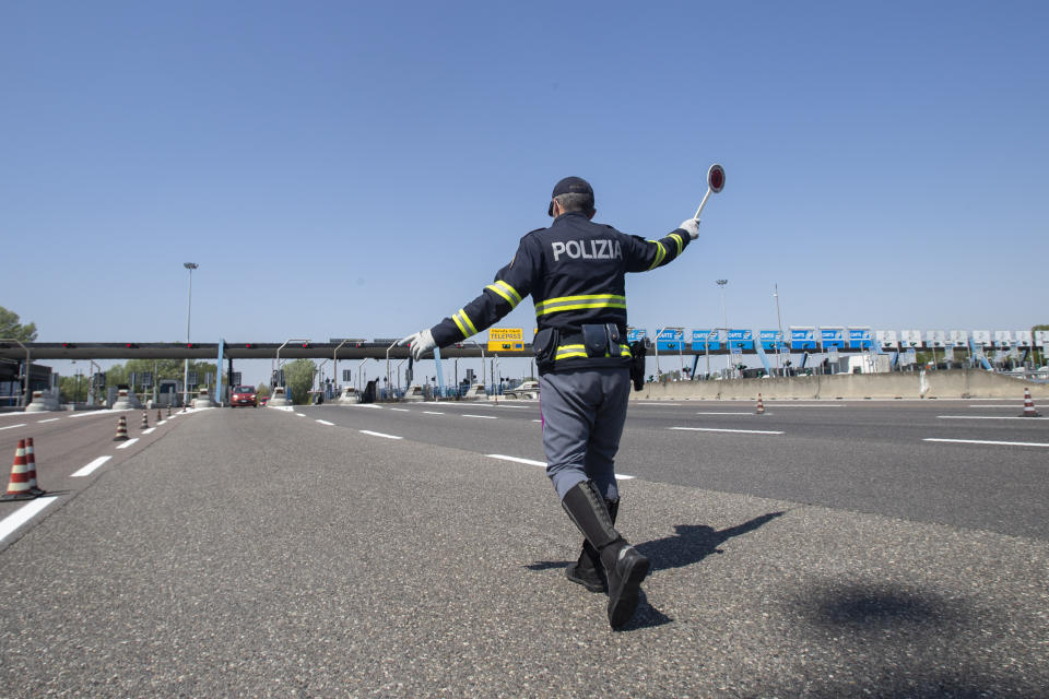 Police officers stop cars at the Melegnano highway barrier entrance, near Milan, Italy, Saturday, April 11, 2020. Using helicopters, drones and stepped-up police checks to make sure Italians don't slip out of their homes for the Easter holiday weekend, Italian authorities are doubling down on their crackdown against violators of the nationwide lockdown decree. The new coronavirus causes mild or moderate symptoms for most people, but for some, especially older adults and people with existing health problems, it can cause more severe illness or death. (AP Photo/Luca Bruno)