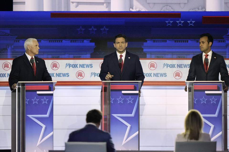 Gov. Ron DeSantis, former vice president Mike Pence and Vivek Ramaswamy stand behinds lecturns as the debate.