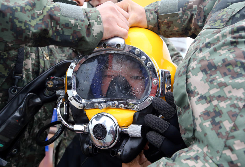 A diver wears a helmet to look for people still missing from the sunken ferry Sewol, in the water off the southern coast near Jindo, South Korea, Saturday, April 26, 2014. A prosecutor investigating the South Korean ferry sinking that left 302 people dead or missing says all 15 crew members involved in the ship's navigation are now in custody. (AP Photo/Yonhap) KOREA OUT