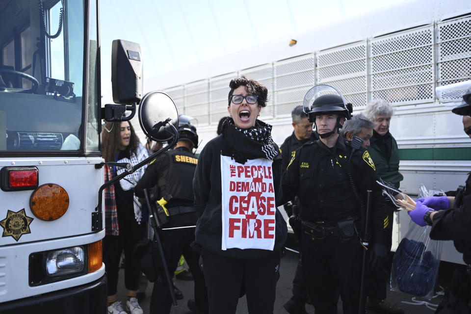 FILE - Police officers detain a protester blocking the San Francisco-Oakland Bay Bridge while demonstrating against the APEC summit and the Israel-Hamas war, Thursday, Nov. 16, 2023, in San Francisco. San Francisco's District Attorney's Office on Monday began charging demonstrators who blocked traffic for hours last month on the Bay Bridge to demand a cease-fire in Gaza.(AP Photo/Noah Berger, File)