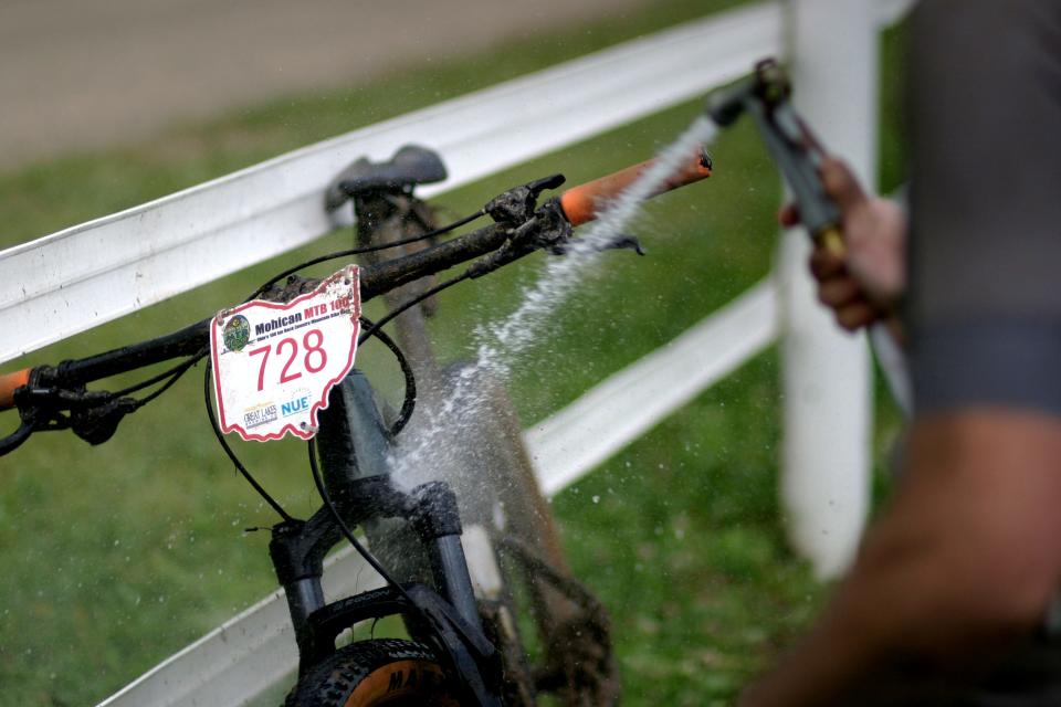 A rider washes the mud off their bike Saturday after the Mohican Mountain Bike Race.