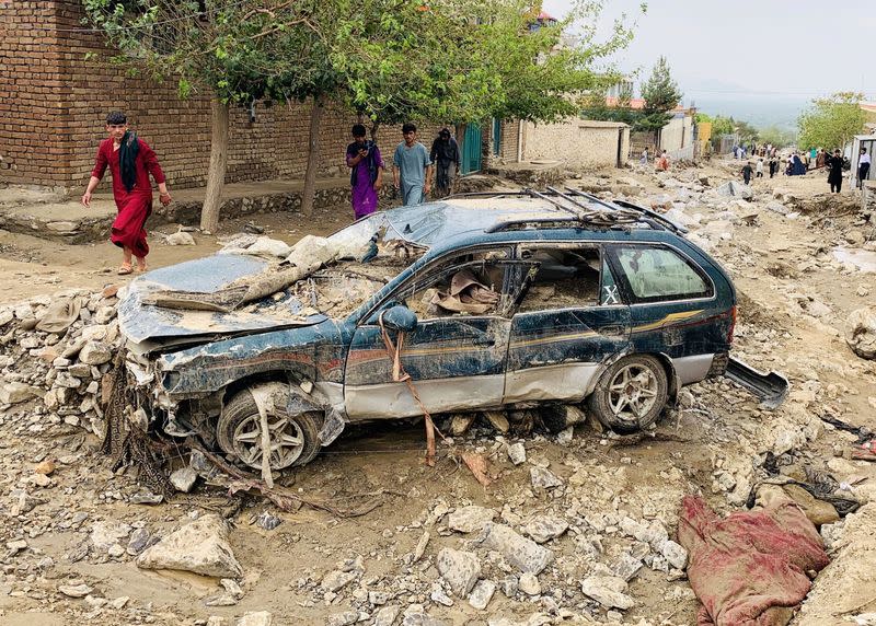 An Afghan man walks past a damaged vehicle after floods in Charikar