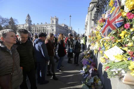 Onlookers view floral tributes on the wall surrounding the Houses of Parliament, following the attack in Westminster earlier in the week, in central London, Britain March 25, 2017. REUTERS/Paul Hackett