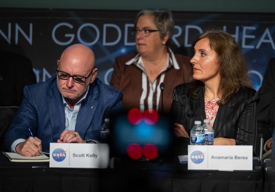 two people seated at a table beneath a nasa logo