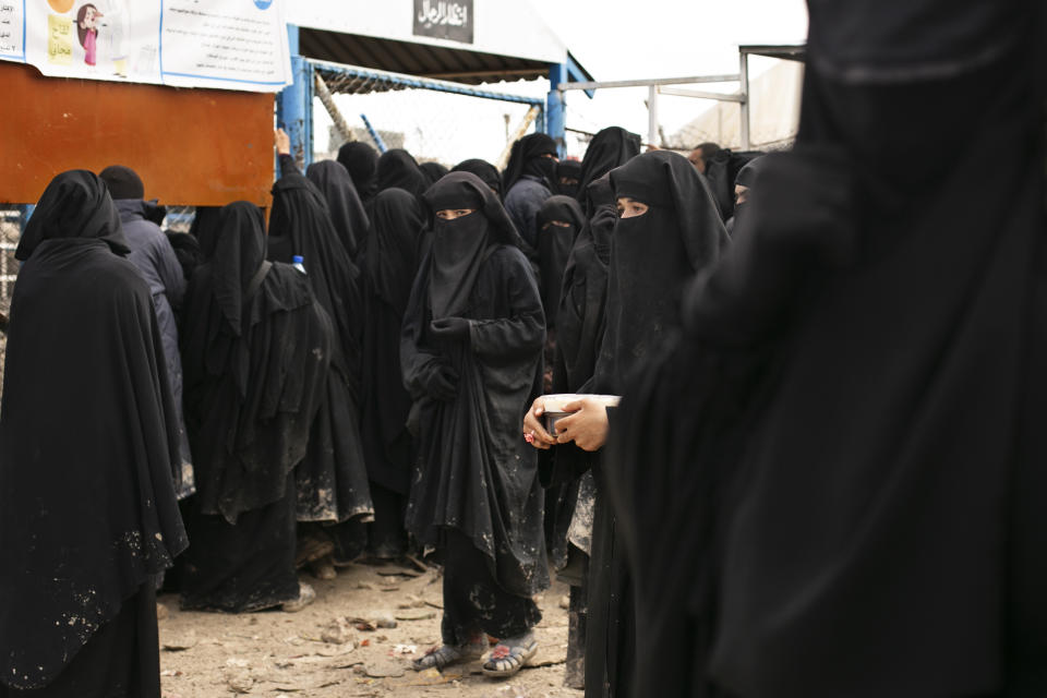 FILE - In this Sunday, March 31, 2019, file, photo, women line up for aid supplies at al-Hol camp in Hasakeh province, Syria. As Turkish troops invade northern Syria and the U.S. abandons its Kurdish allies, there are renewed fears of a prison break in the camp that could give new life to the extremist group. (AP Photo/Maya Alleruzzo, File)