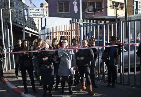 Passers-by stand behind a police tape at the scene of a stabbing attack in Tel Aviv January 21, 2015. REUTERS/Nir Elias