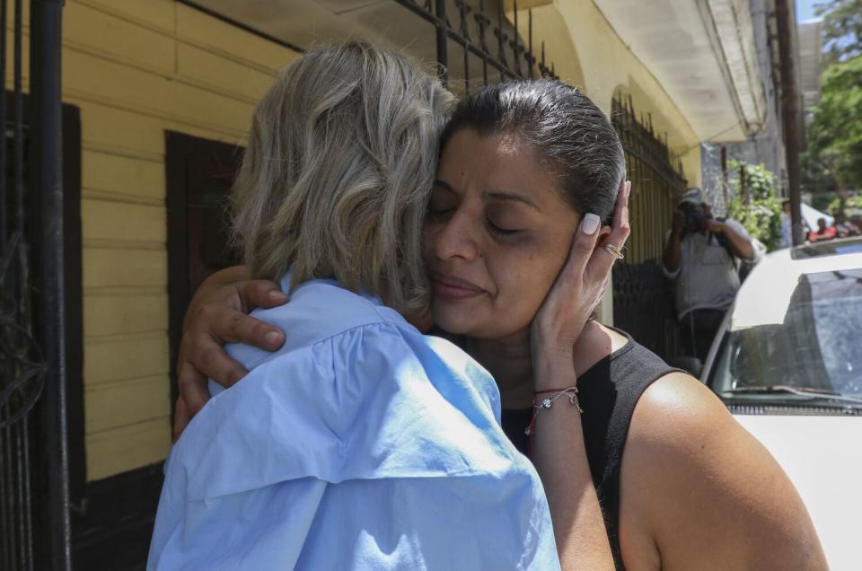 Two women embrace.