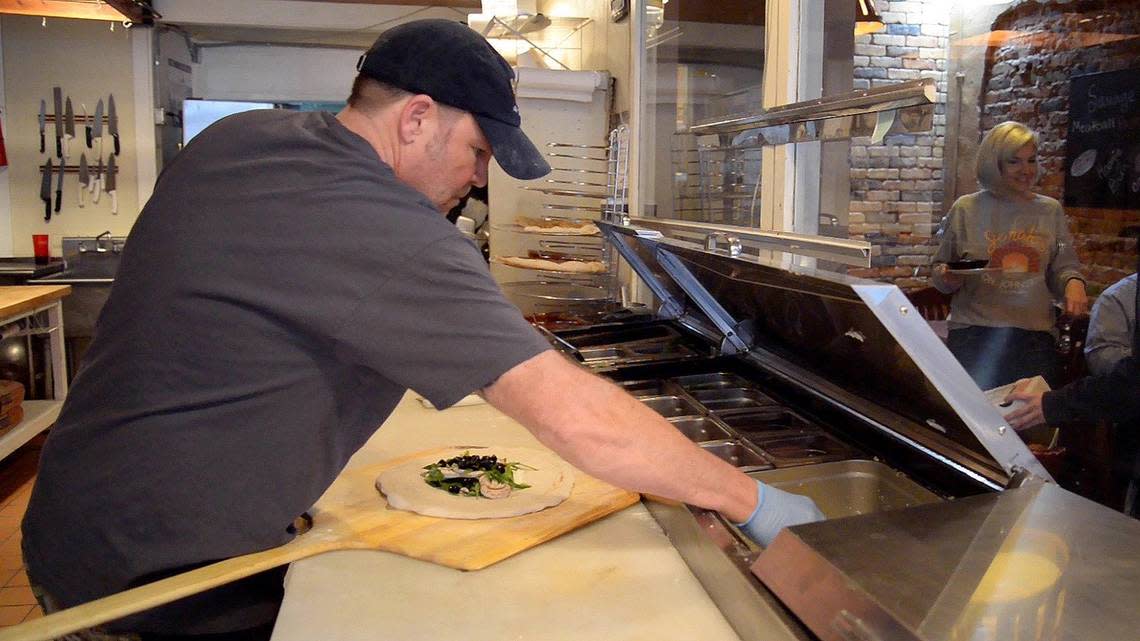 Eric Thomas, owner of Jonah’s on Johnston Pizzeria, makes a calzone while his wife, Laurie, serves customers. “What we want is a local place where people love to come and hang out and eat and can be their weekly place to come with their family,” Laurie says.