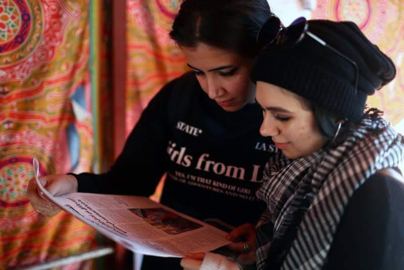 Iraqi women demonstrators read Tuktuk newspaper during the ongoing anti-government protests, in Baghdad