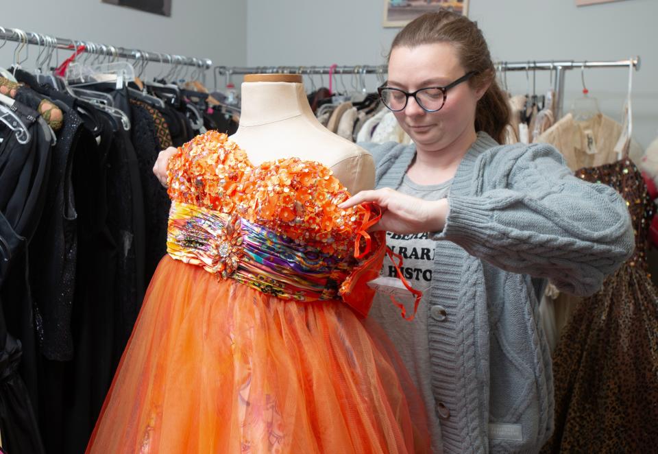 Wicked Thrift store owner Missy Jones fits a $125 Mori Lee orange floral ballgown onto a mannequin at her South Yarmouth store.