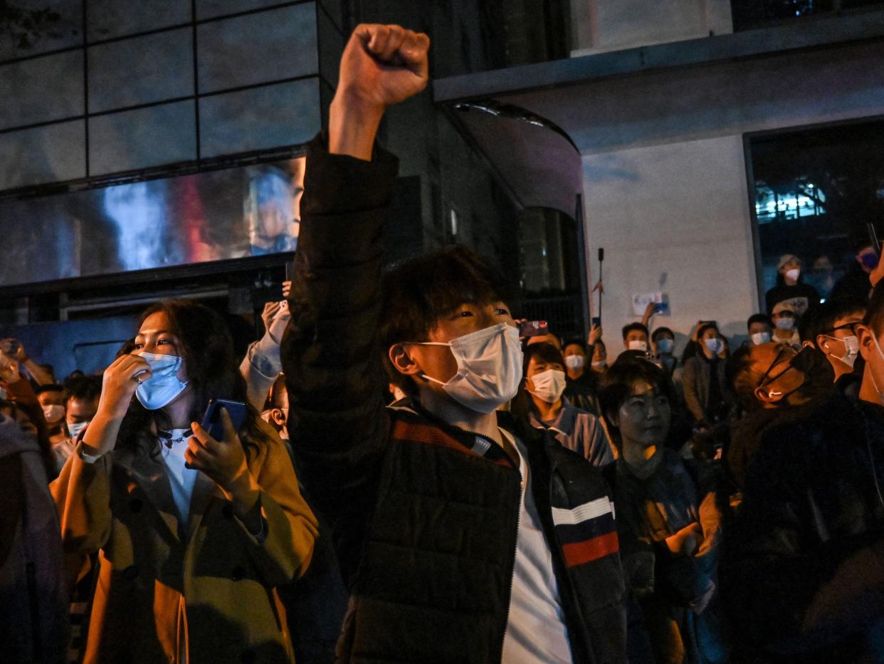 People sing slogans while gathering on a street in Shanghai on November 27, 2022, where protests against China's zero-Covid policy took place the night before following a deadly fire in Urumqi, the capital of the Xinjiang region