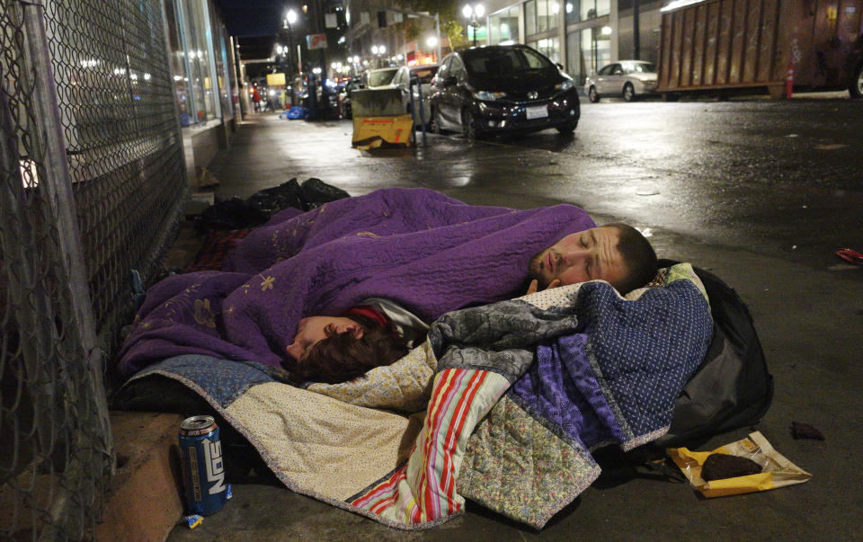 FILE - In this Sept. 18, 2017, file photo, two people sleep on a street in downtown Portland, Ore. A measure to tax the incomes of the wealthiest residents and the profits of the biggest businesses to raise $2.5 billion over a decade to address the homeless crisis sailed to victory in the Portland, Oregon metropolitan region even as the state faces crippling revenue losses and record-high unemployment. Nearly 60% of voters in the three counties that make up the greater Portland region approved the tax amid a greatest economic turmoil in years, a sign of just how intractable the homeless problem has become in the liberal Pacific Northwest city. (AP Photo/Ted S. Warren, File)
