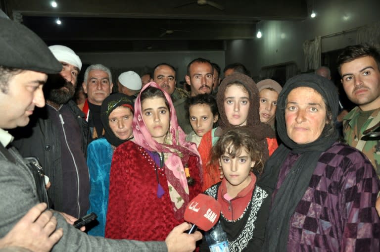 Syrian Druze women and children, freed from more than three months' captivity at the hands of the Islamic State group, are welcomed home by their families on November 9, 2018 are welcomed hom by their A handout picture released by the official Syrian Arab News Agency (SANA) on November 9, 2018 shows a group of Druze women and children, abducted in July from Sweida by the Islamic State group, pose for a picture as they are being welcomed by relatives upon their arrival overnight in their hometown in the southern Syrian province of Sweida