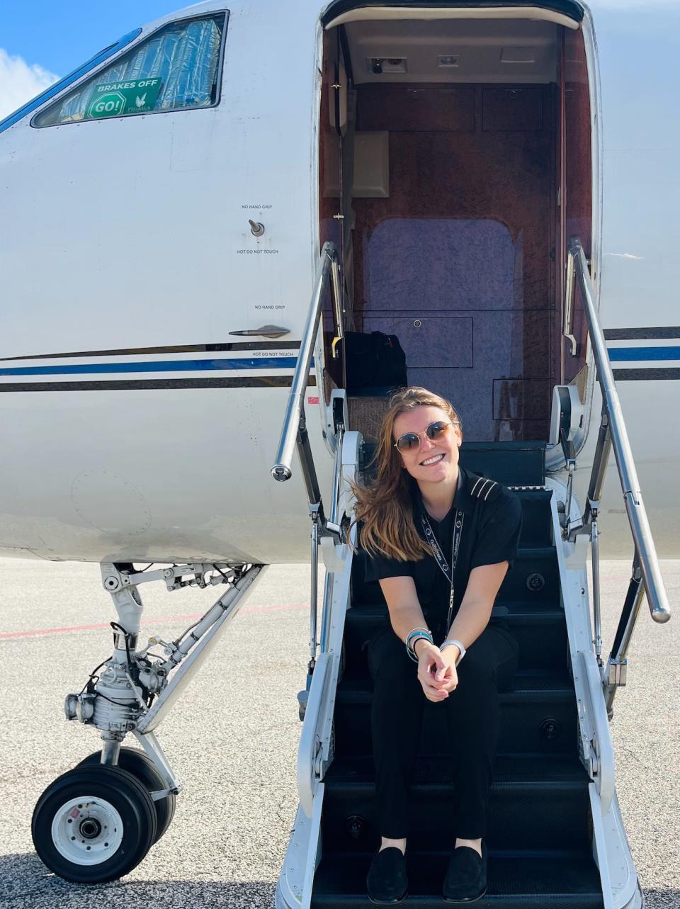 Female pilot sits on steps up to a Gulfstream jet