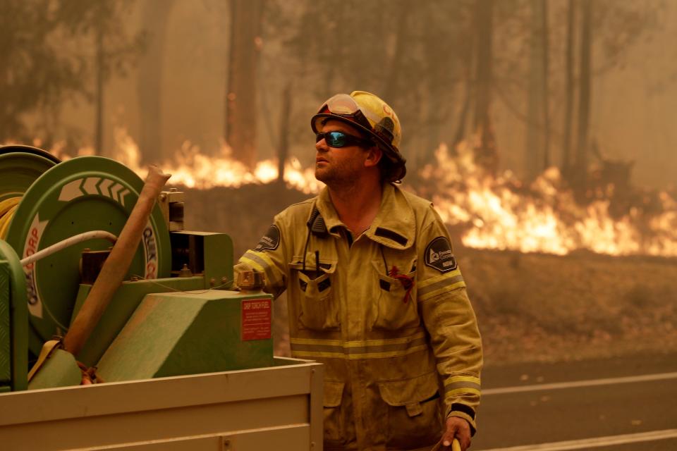 A Forest Corporation worker manages a fire hose as he battles a fire near Moruya, Australia, Saturday, Jan. 4, 2020.