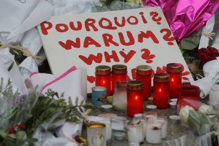 A sign asking why is seen amongst candles and flowers outside the Bataclan music hall following a series of shooting attacks on Friday in Paris, November 16, 2015. REUTERS/Christian Hartmann