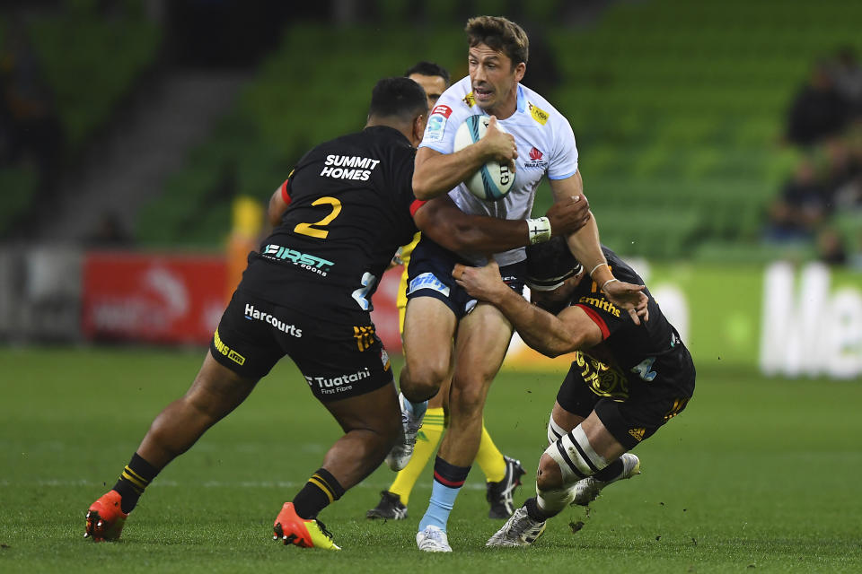 Luke Jacobson of the Chiefs, right, tackles Jake Gordon of the Waratahs, center, during the Super Rugby Pacific Round 10 match between the Waikato Chiefs and the NSW Waratahs at AAMI Park in Melbourne, Friday, April 22, 2022. (James Ross/AAP Image via AP)