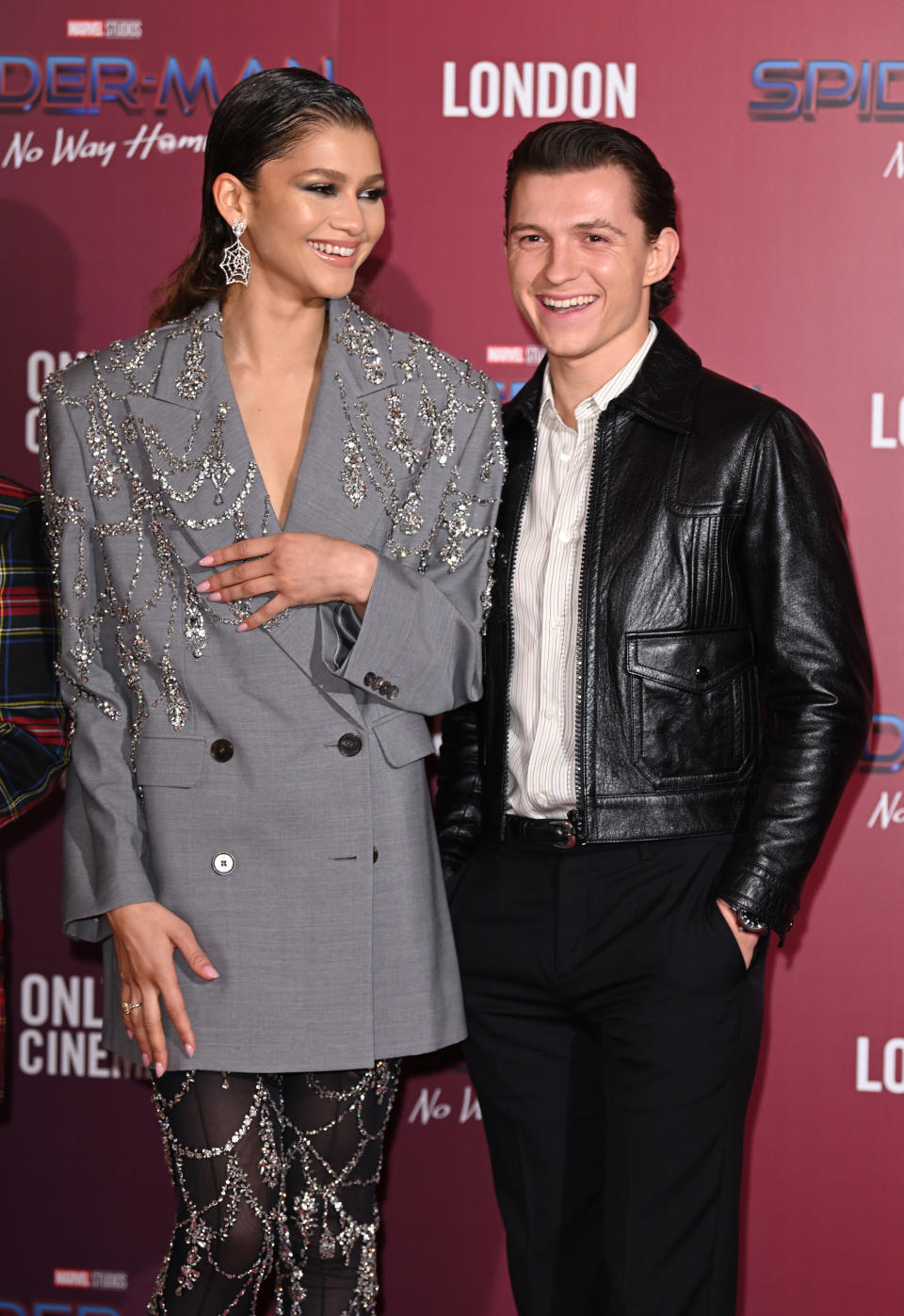 Zendaya in a gray blazer with sparkling embellishments and Tom Holland in a black leather jacket and white shirt at the Spiderman: No Way Home premiere in London