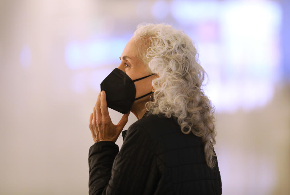 Dr. Barbara Ferrer holds a protective mask to her face.