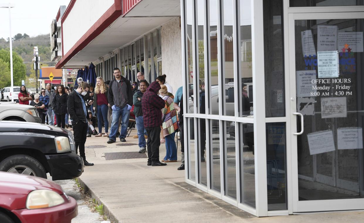 A line of around fifty people extends from the door of Arkansas Workforce Center in Fayetteville, Ark. on Monday, March 30, 2020.