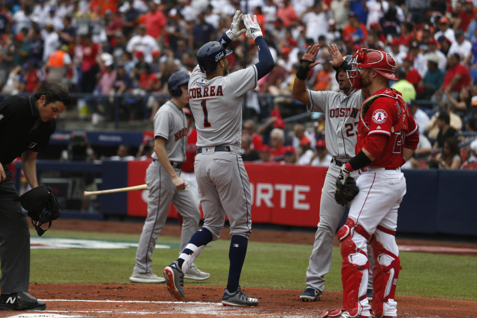Houston Astros' Carlos Correa, center, is congratulated by teammate Michael Brantley as he crosses home after hitting a home run in the second inning of a baseball game against the Los Angeles Angels, in Monterrey, Mexico, Sunday, May 5, 2019. (AP Photo/Rebecca Blackwell)