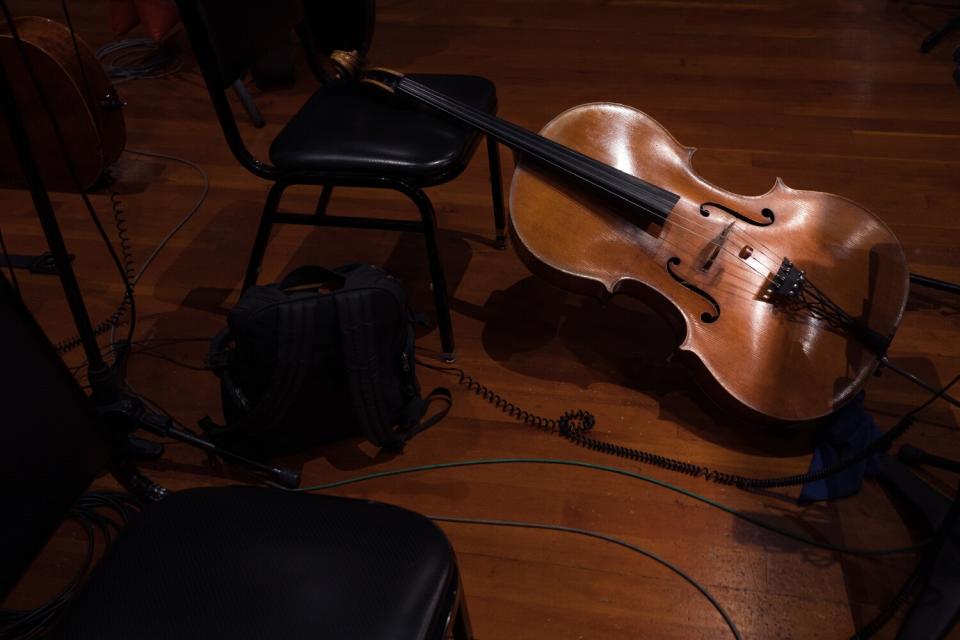 A cello is seen leaning against a chair in a band rehearsal space