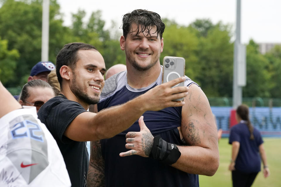 Tennessee Titans tackle Taylor Lewan poses for a photo with a fan after a training camp practice at the NFL football team's facility Saturday, July 30, 2022, in Nashville, Tenn. (AP Photo/Mark Humphrey)