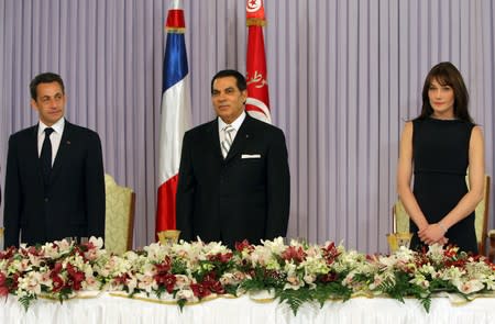 FILE PHOTO: France's President Sarkozy speaks as Tunisia's President Ben Ali and France's first lady Carla Bruni-Sarkozy listen before a dinner in Tunis