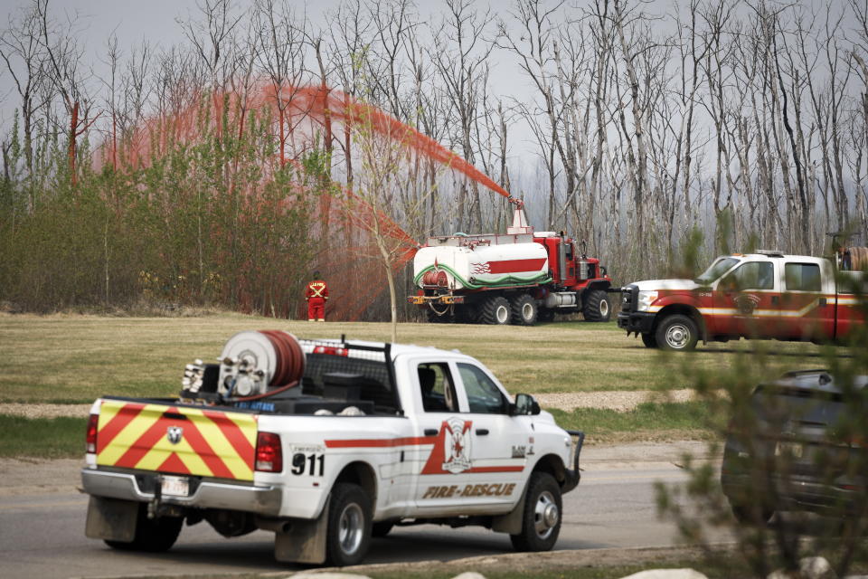 A pumper truck sprays fire retardant on trees around the evacuated neighborhood of Beacon Hill in Fort McMurray, Alberta, Canada, on Wednesday, May 15, 2024. (Jeff McIntosh/The Canadian Press via AP)