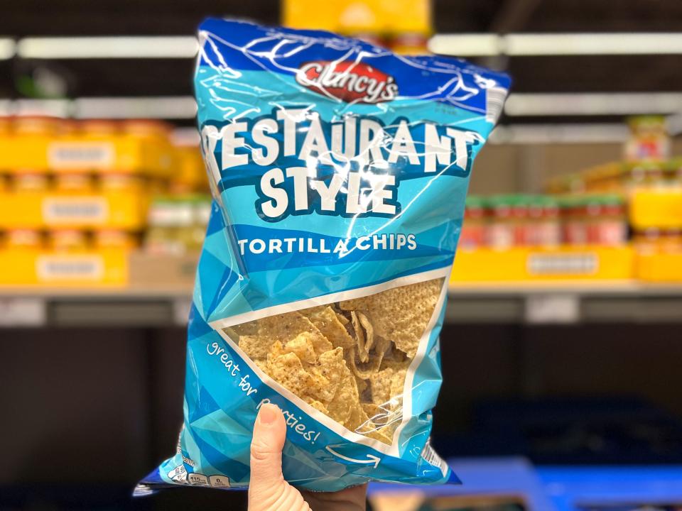 A hand holding a bag of Clancy's restaurant-style tortilla chips.