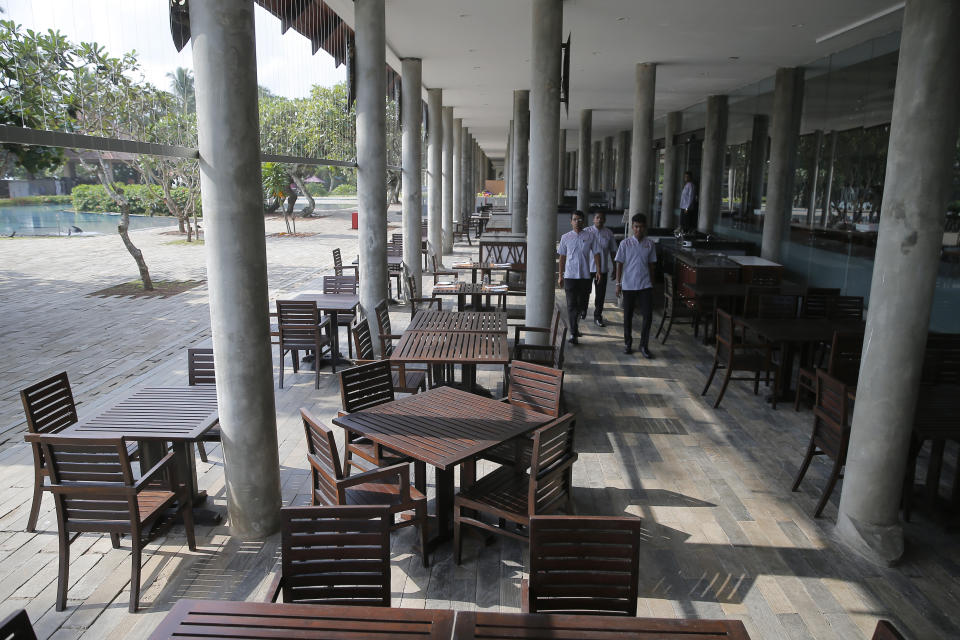 FILE - In this Friday, May 10, 2019, file photo, hotel staff walk past an empty restaurant at a hotel in Hikkaduwa, Sri Lanka. The state-run tourism agency says the arrival of tourists in Sri Lanka rapidly declined in June, dealing a severe blow to the lucrative industry in the aftermath of the Easter suicide bombings that killed more than 250 people. Sri Lanka Tourism Development Authority said Wednesday, July 3, there were 63,072 tourist visits to Sri Lanka last month, a drop of 57% compared with June 2018, when the number was 146,828.(AP Photo/Eranga Jayawardena, File)