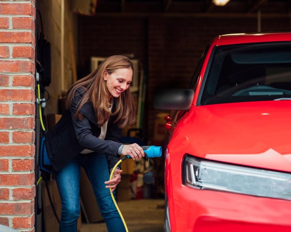 woman charging red electric car