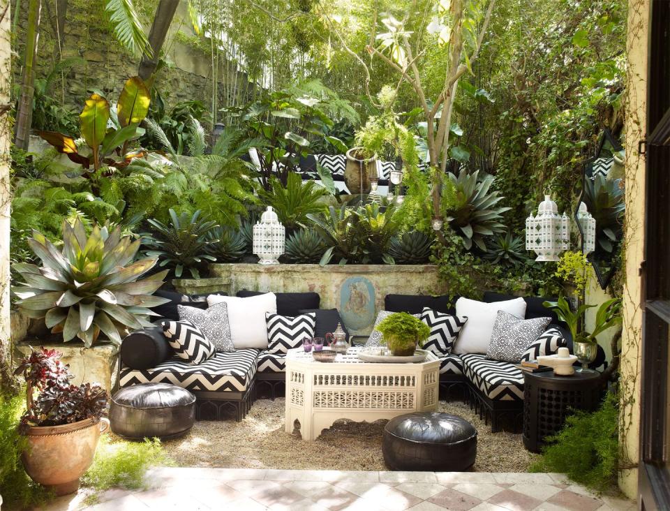 verdant outdoor room with poofs and lanterns and seating area and terra cotta floor