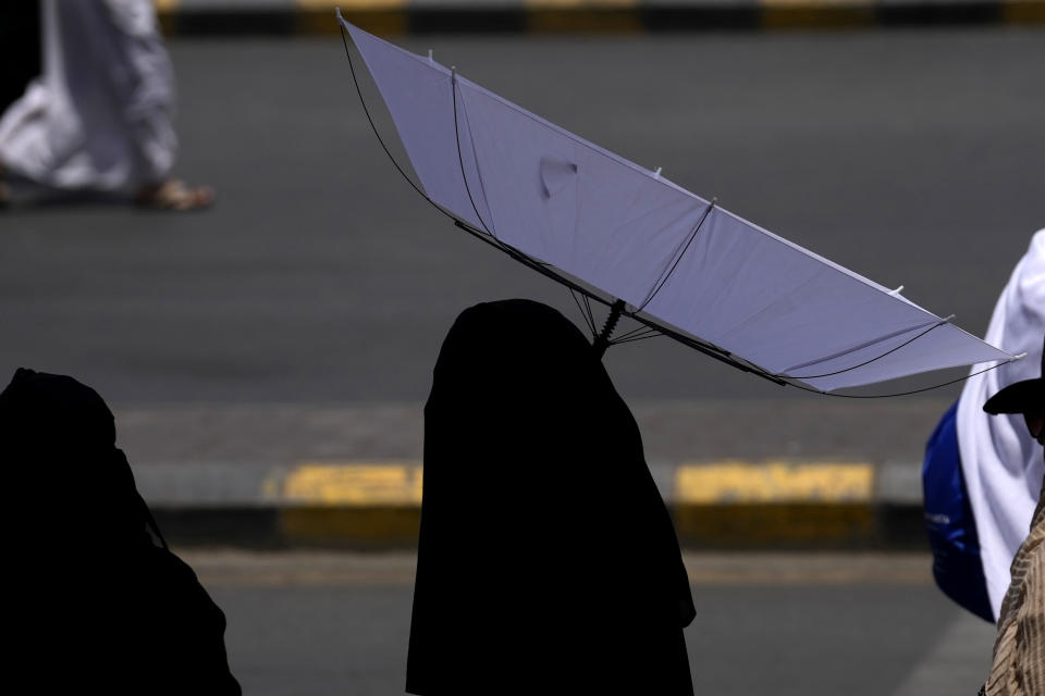 Una mujer se protege del sol con un paraguas tras una oración en la Gran Mezquita, durante la peregrinación anual del haj, en La Meca, Arabia Saudí, el 13 de junio de 2024. (AP Foto/Rafiq Maqbool)